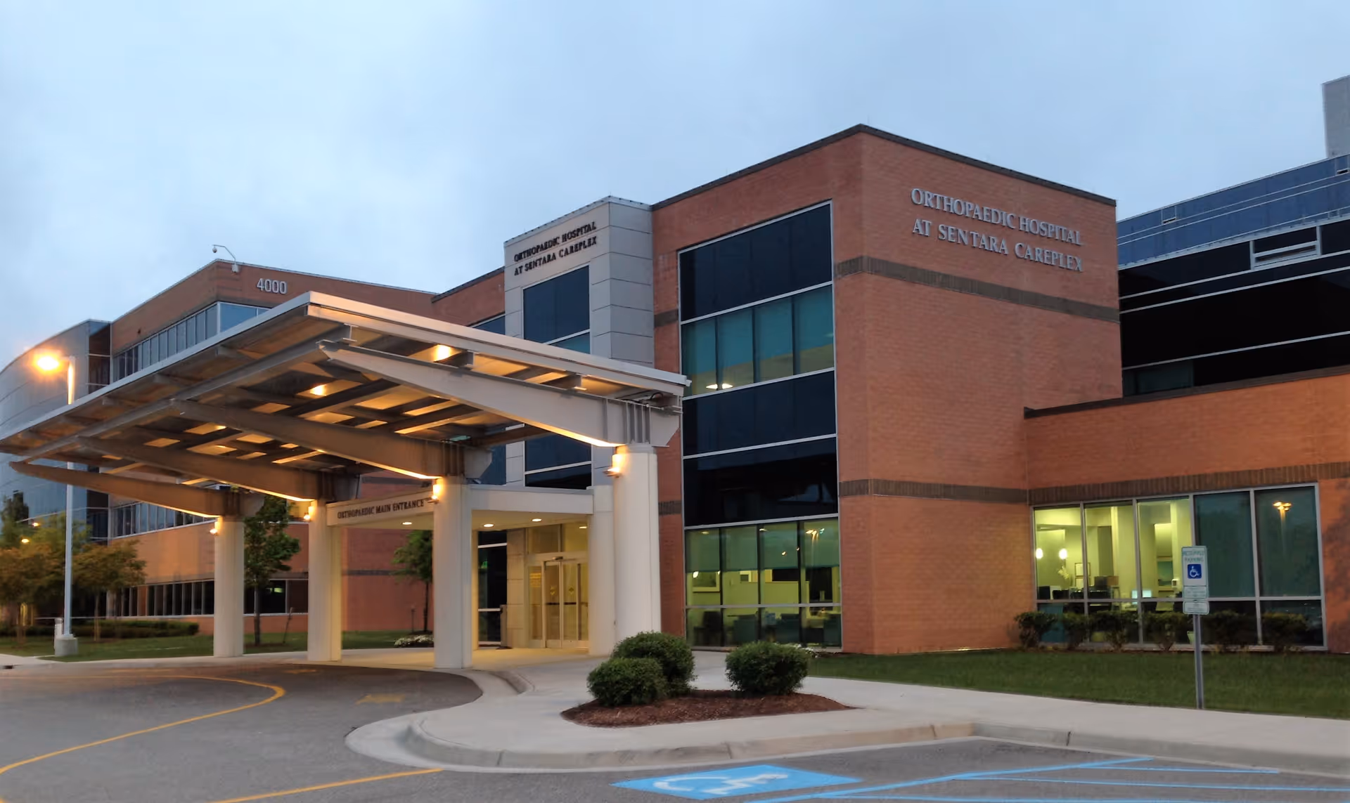 Exterior view of a brick hospital-like building with a large covered entrance.