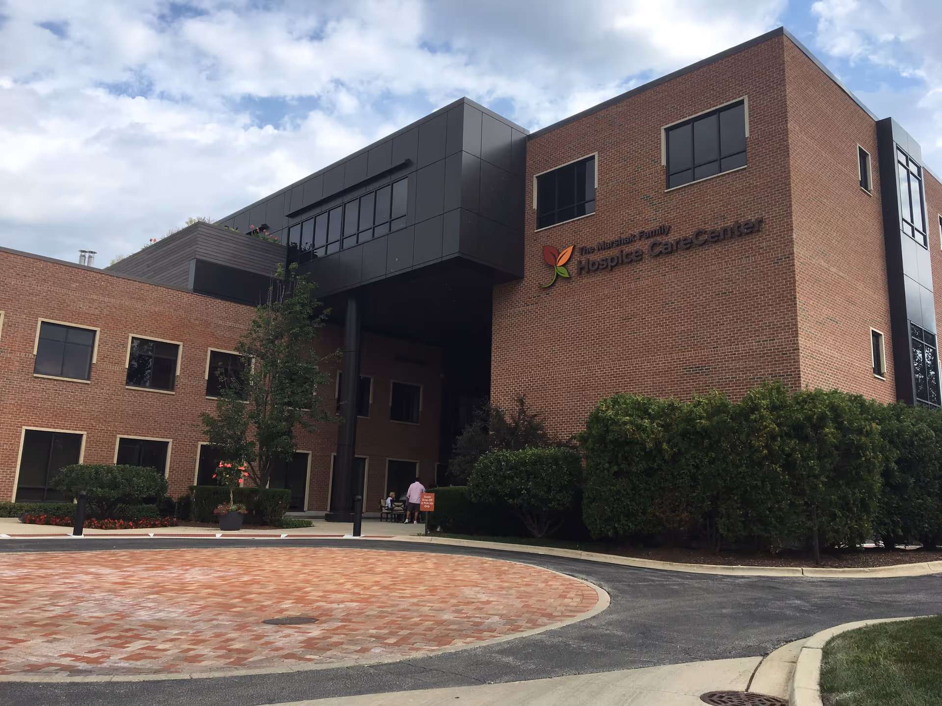 Exterior view of a brick senior care center with signage and landscaping.
