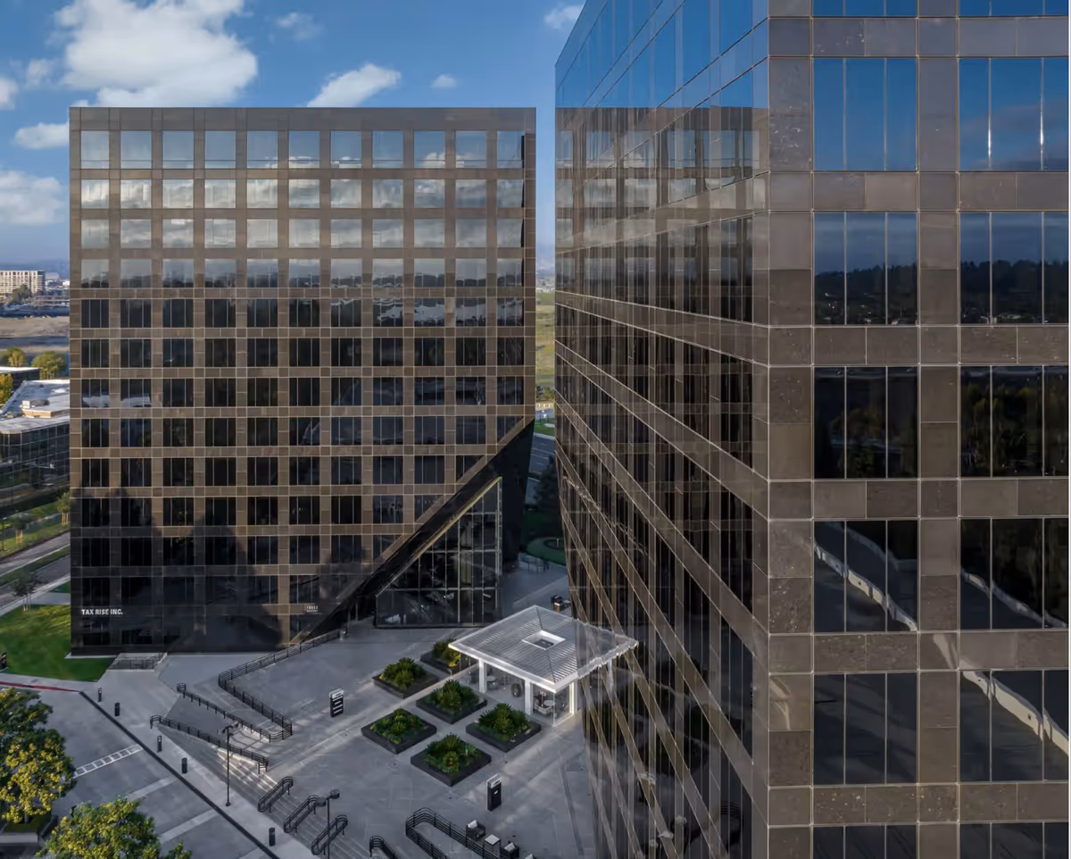 Aerial view of two modern glass office buildings with a shared courtyard plaza