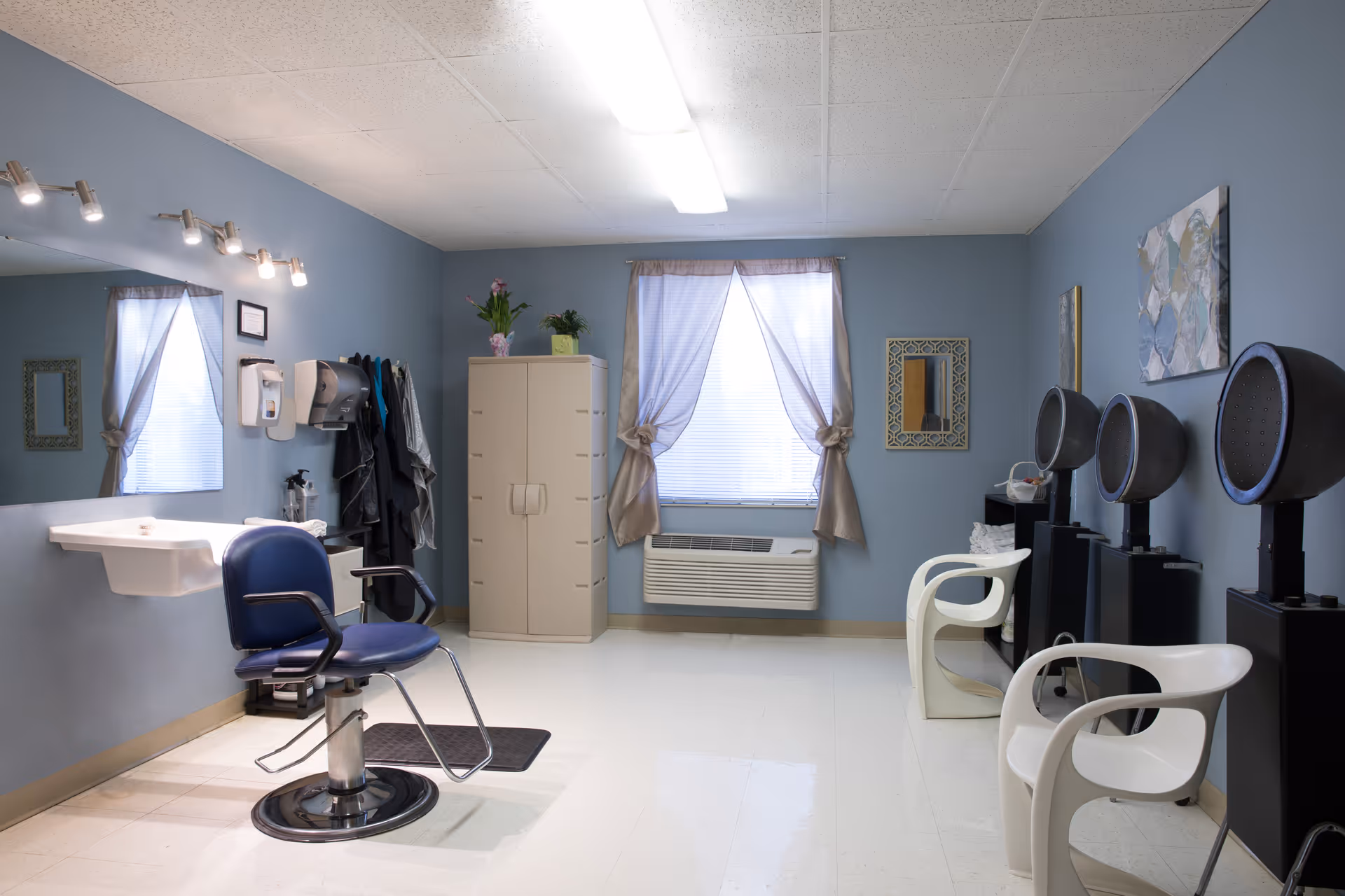 Salon area inside a senior facility with styling chair, hair dryers, and cabinetry.