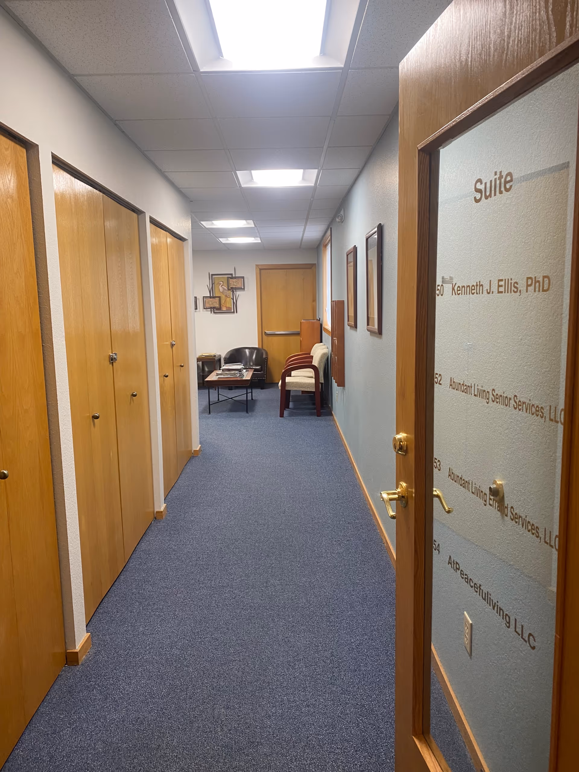 Interior hallway in a senior living facility with closed doors and seating at end