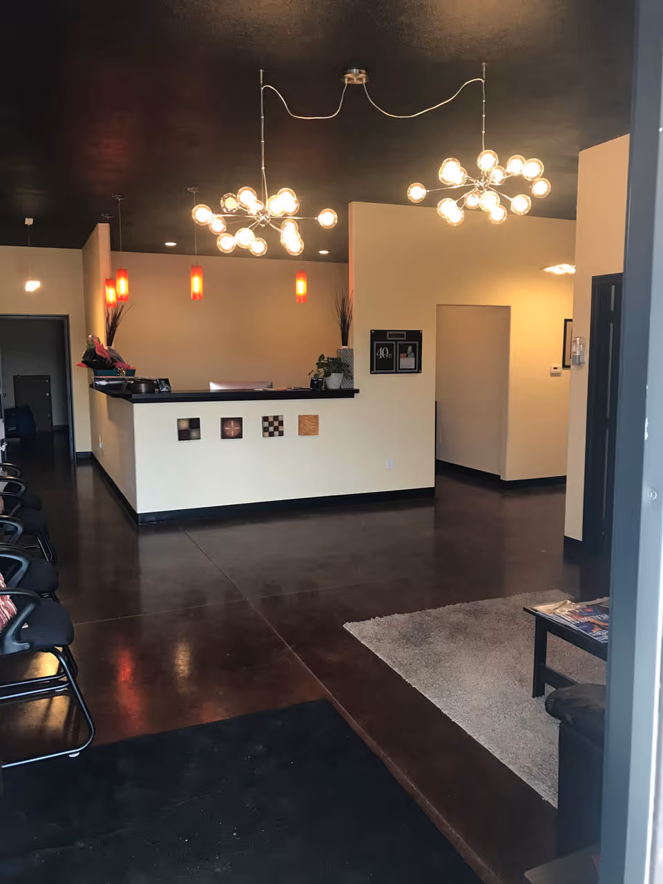 Reception area with a curved counter, modern chandeliers, and seating in a senior living lobby.