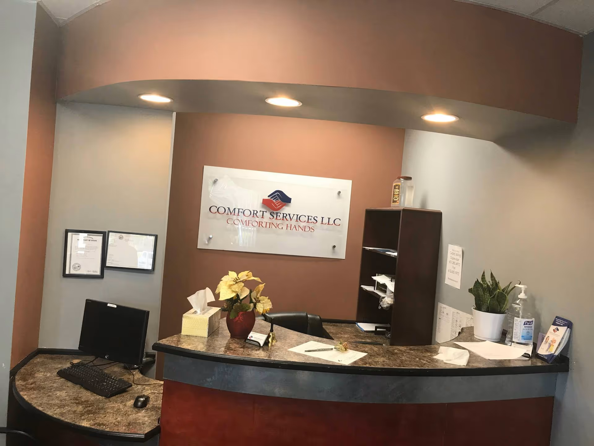 Reception desk with marbled counter, Comfort Services LLC sign, plants, and paperwork.