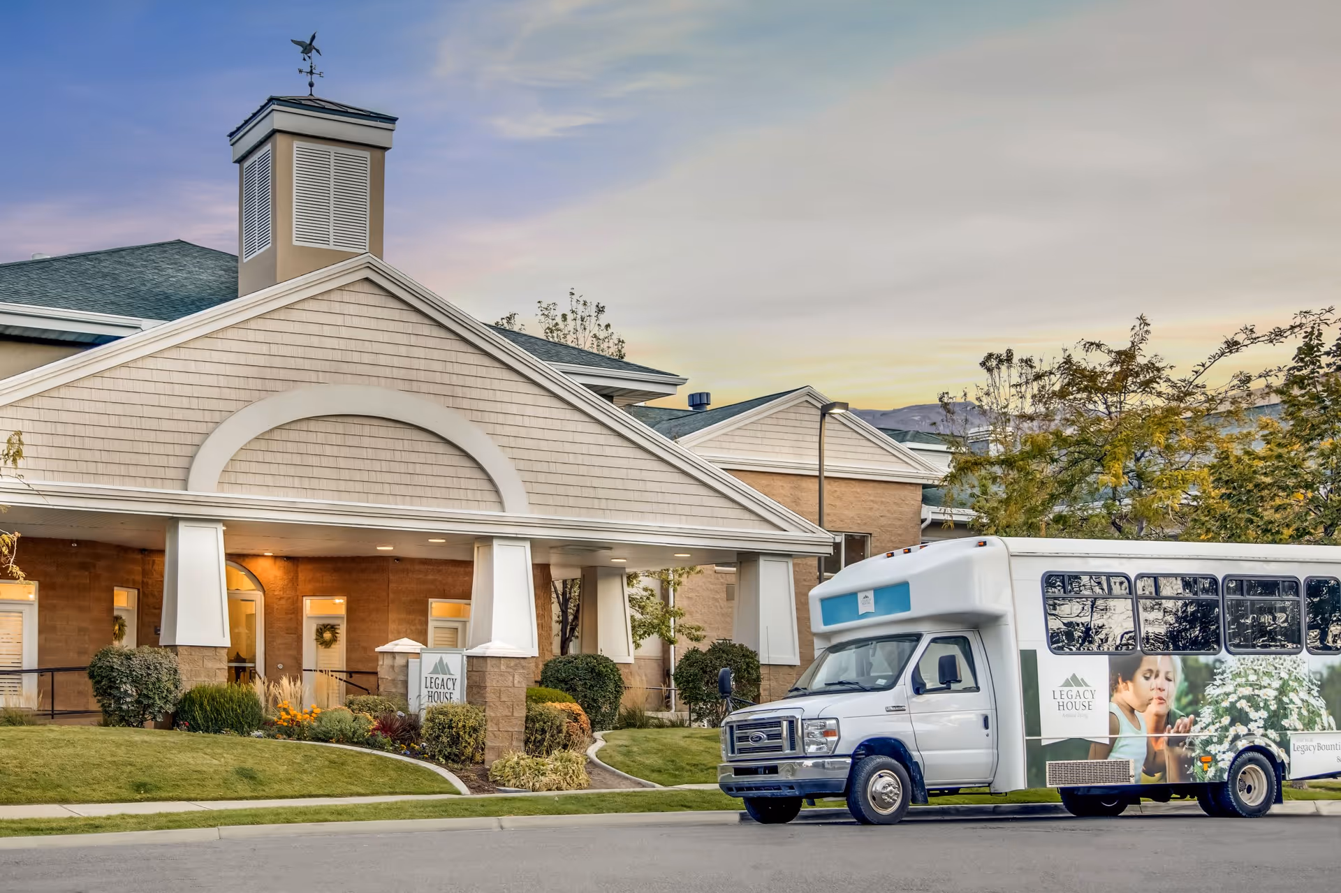Front entrance of a senior living facility with a bus parked outside.
