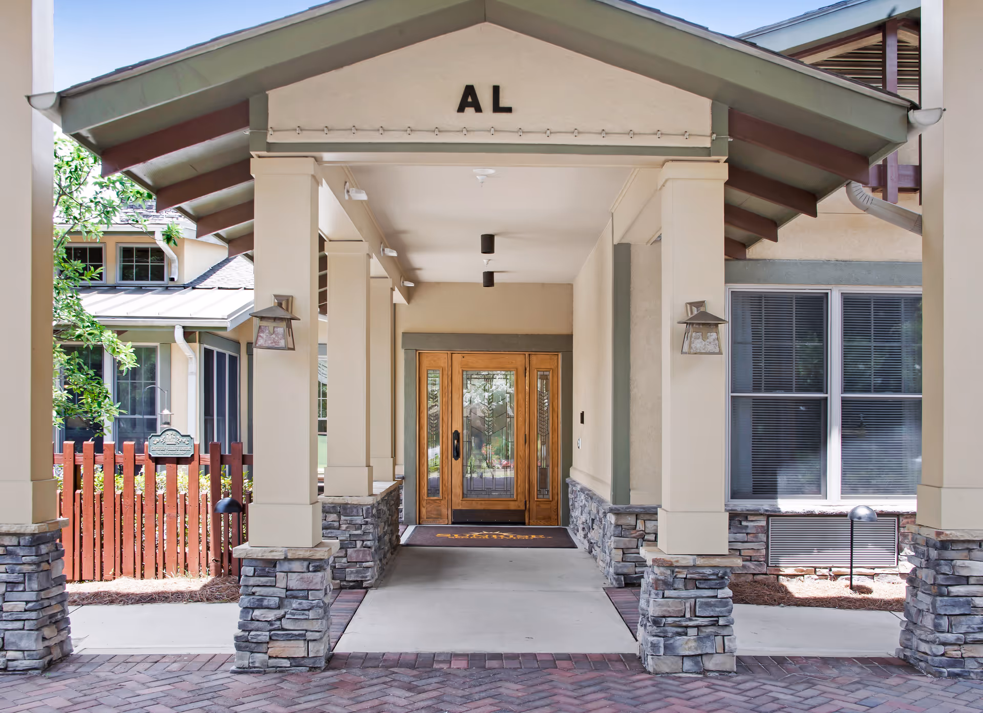 Front entrance of Sunrise at Webb Gin with wooden doors and stone pillars.