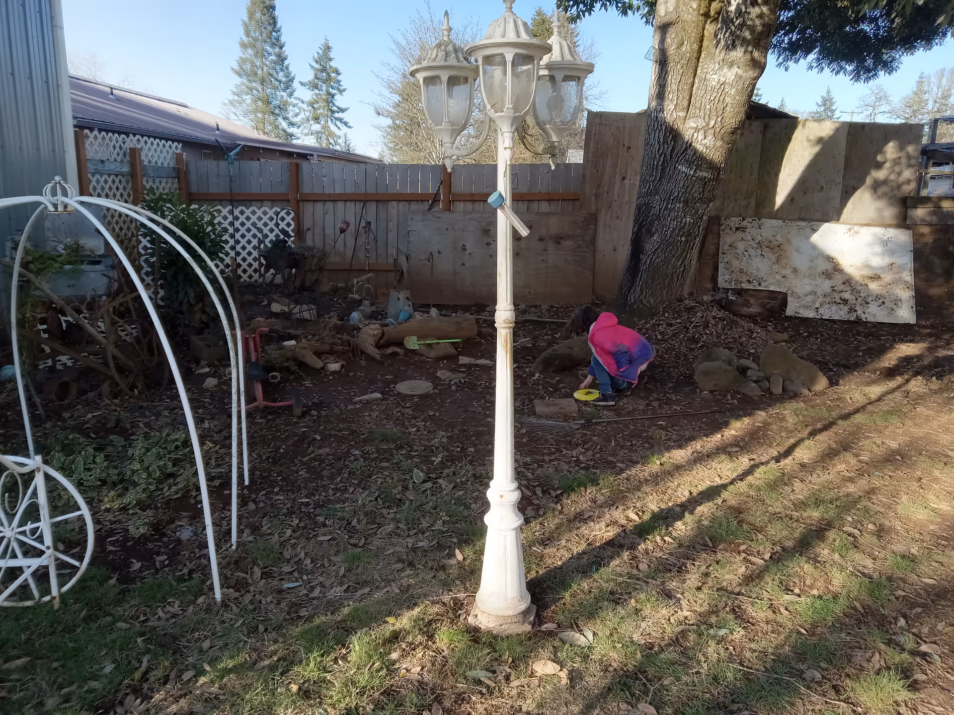 Outdoor backyard at CJ Cares LLC with a lamp post, tree, and a child playing.