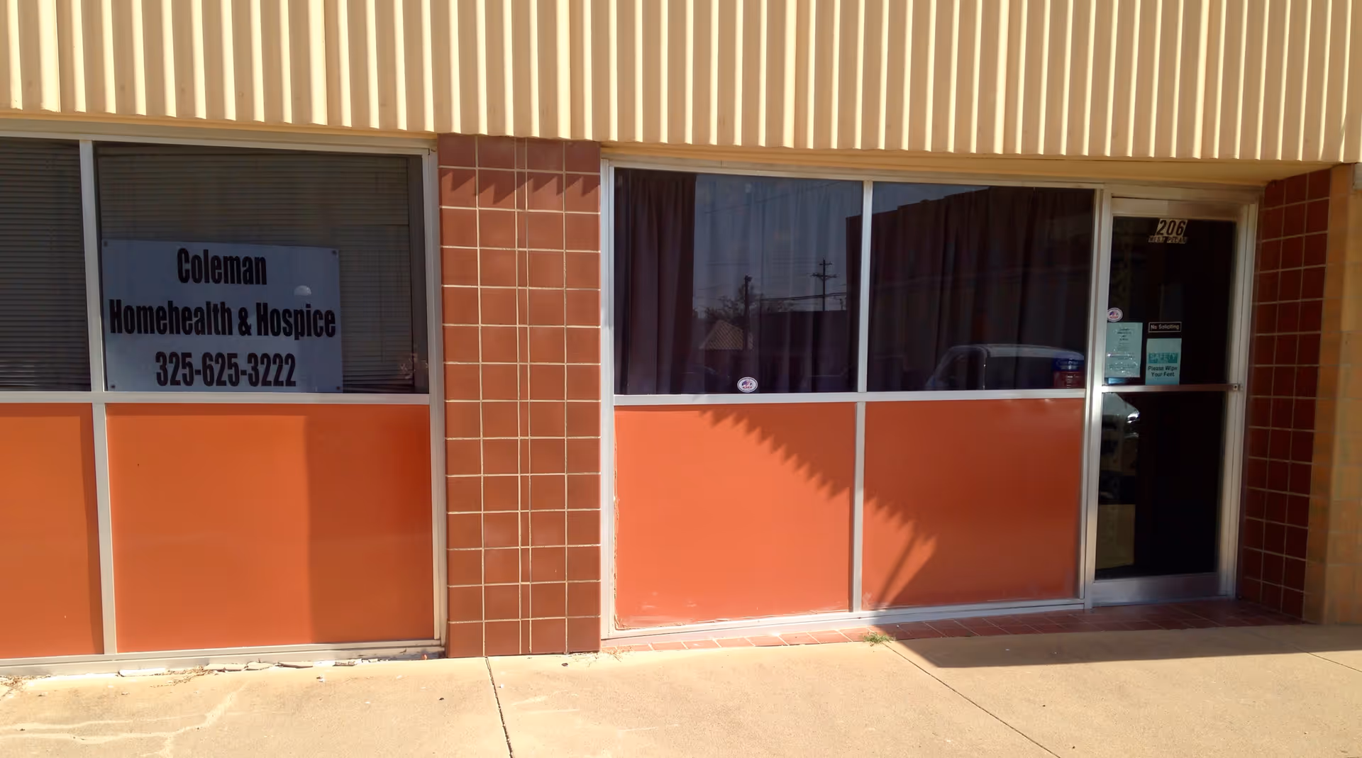 Exterior storefront with Coleman Home Health and Hospice sign, glass doors, and orange-tiled facade.