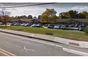 Front view of Royal Westerly senior living facility with parked cars and fall-colored trees.