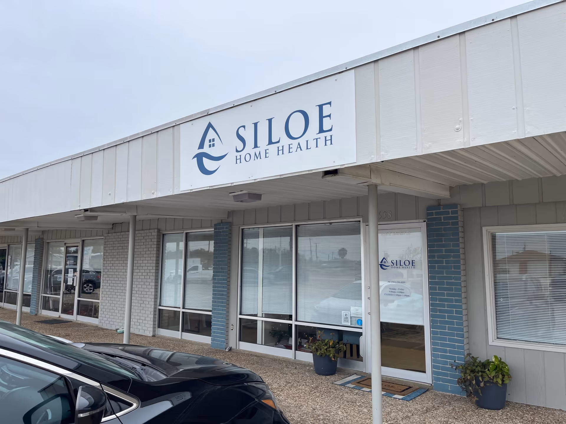 Exterior view of Siloe Home Health building with entrance doors, signage, and a parked car.