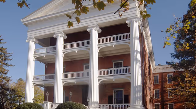 Historic brick building with white columns and balconies on a sunny day.
