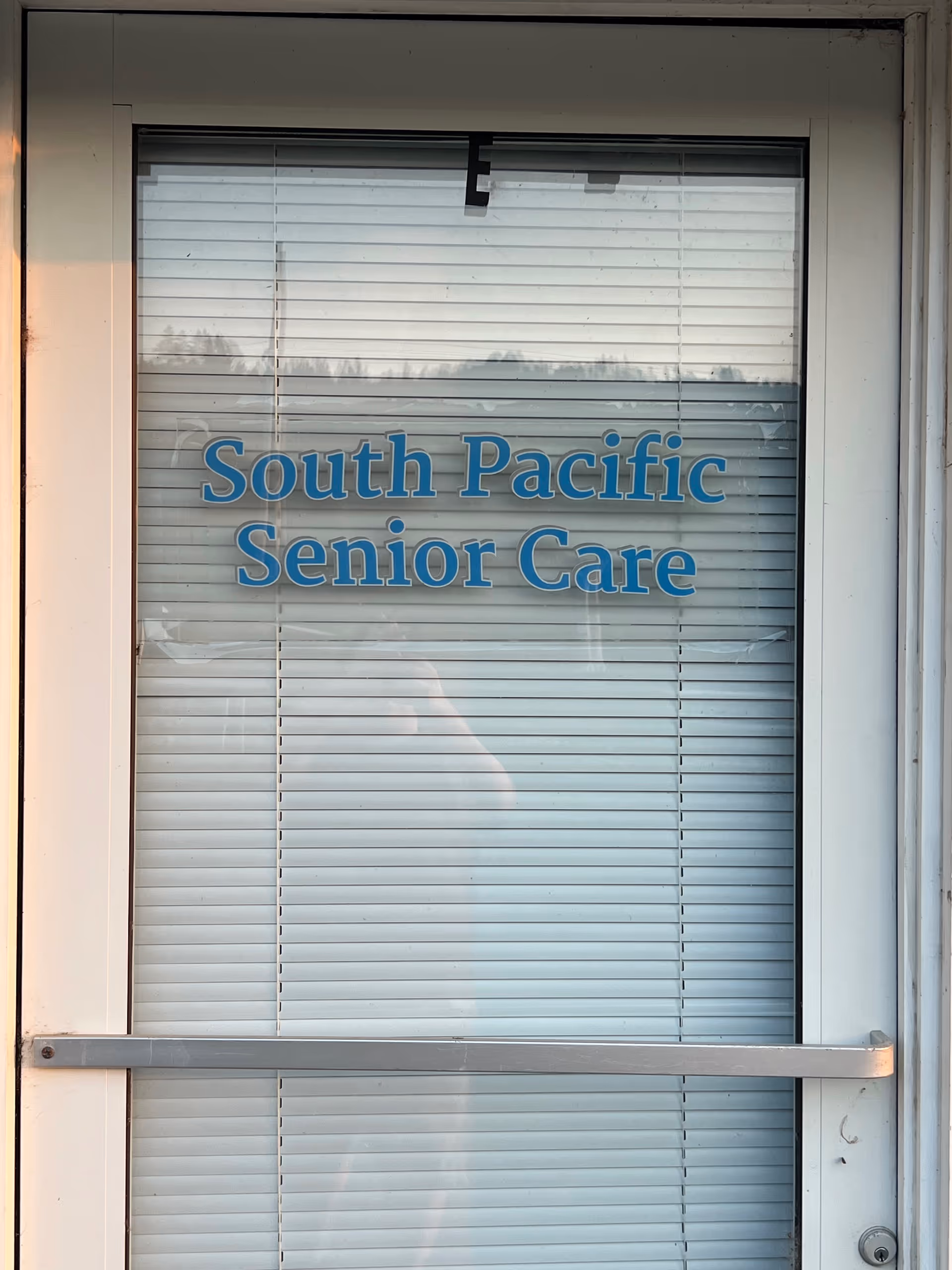Glass door with blinds showing the blue 'South Pacific Senior Care' sign.