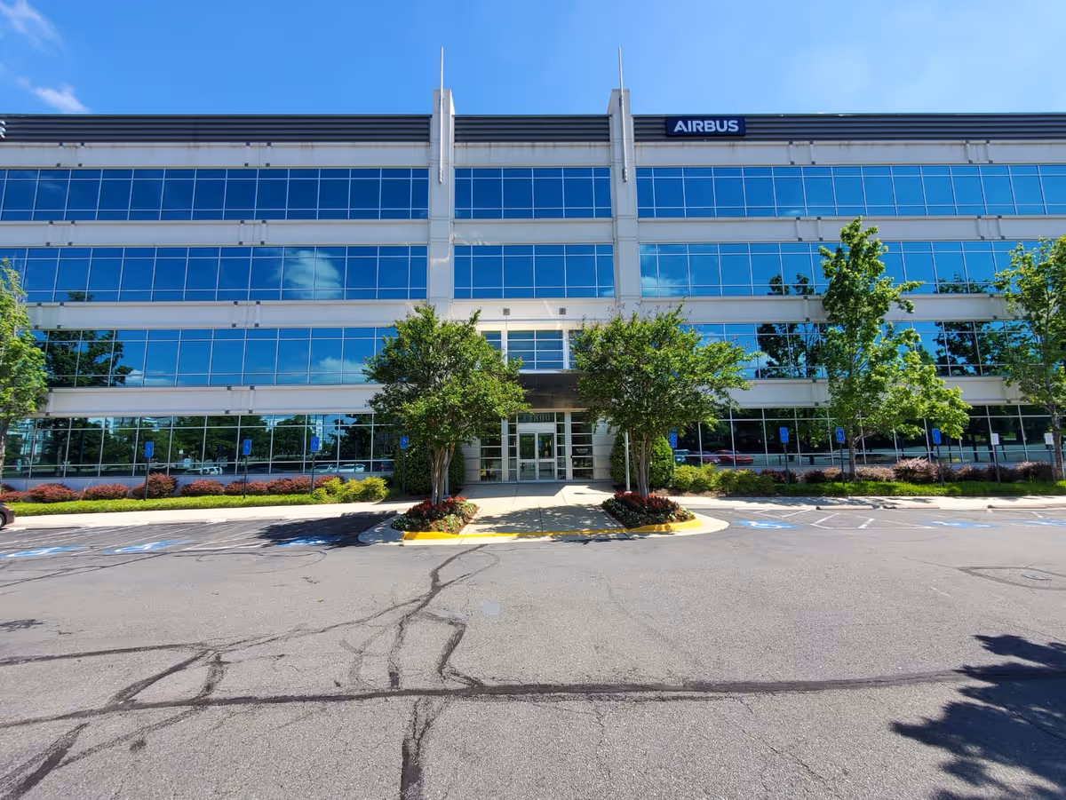 Front view of a glass-front Airbus corporate building with a parking lot.