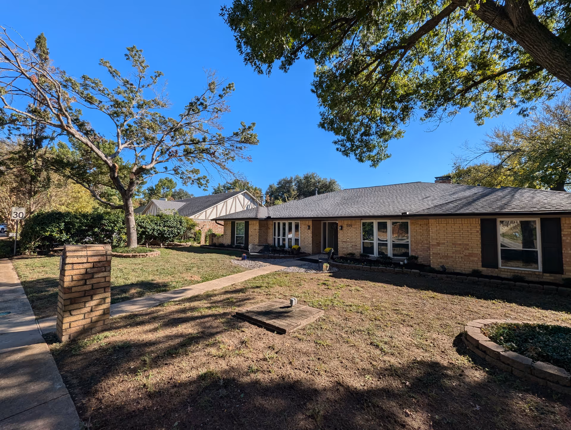 Single-story brick senior care facility exterior with a front yard and trees.