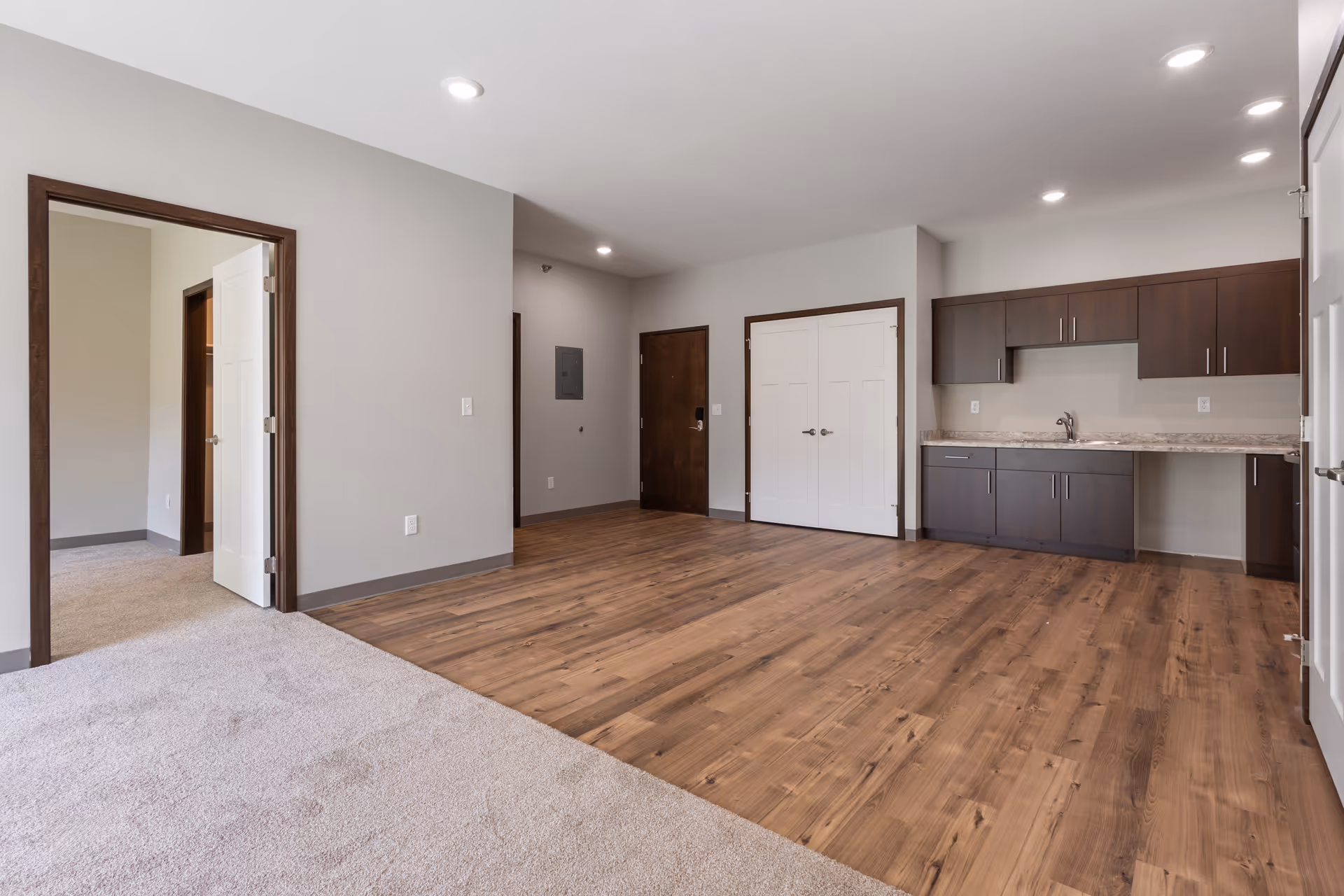 Open living area with wood floors and a kitchenette along the back wall.