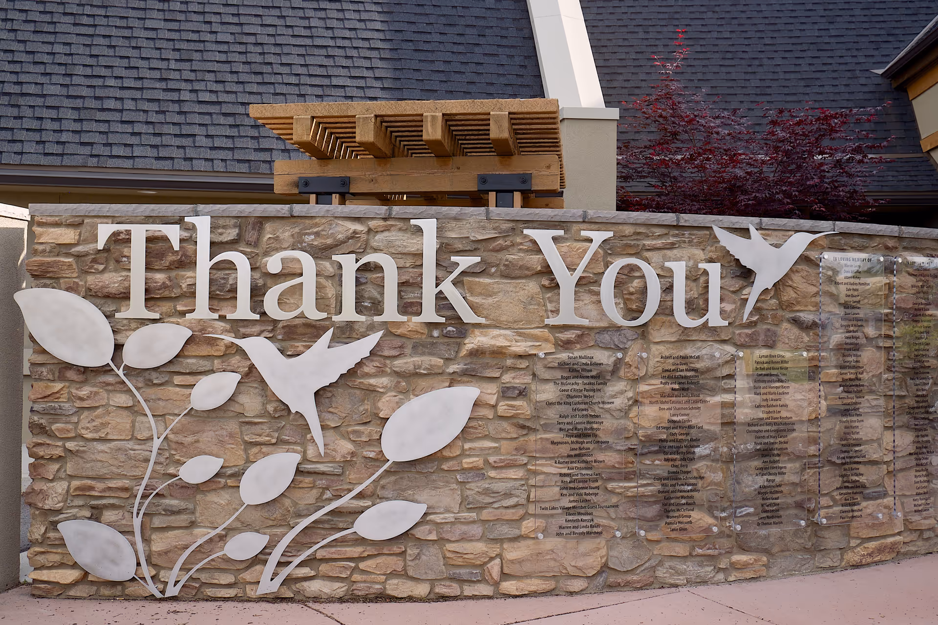 Stone wall front with large 'Thank You' sign and decorative white leaves and birds.