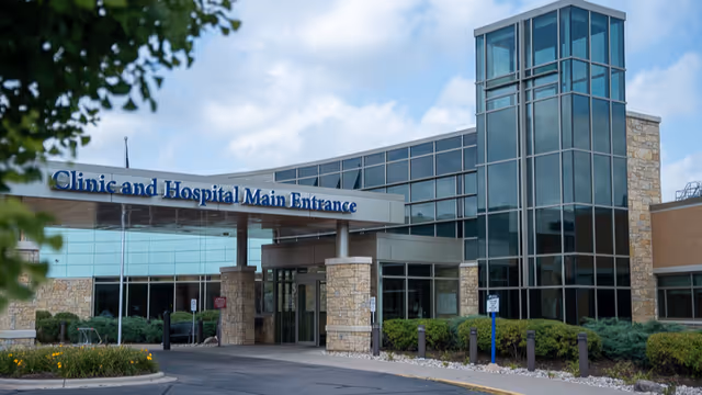 Front entrance of a modern medical facility with glass walls and stone pillars.