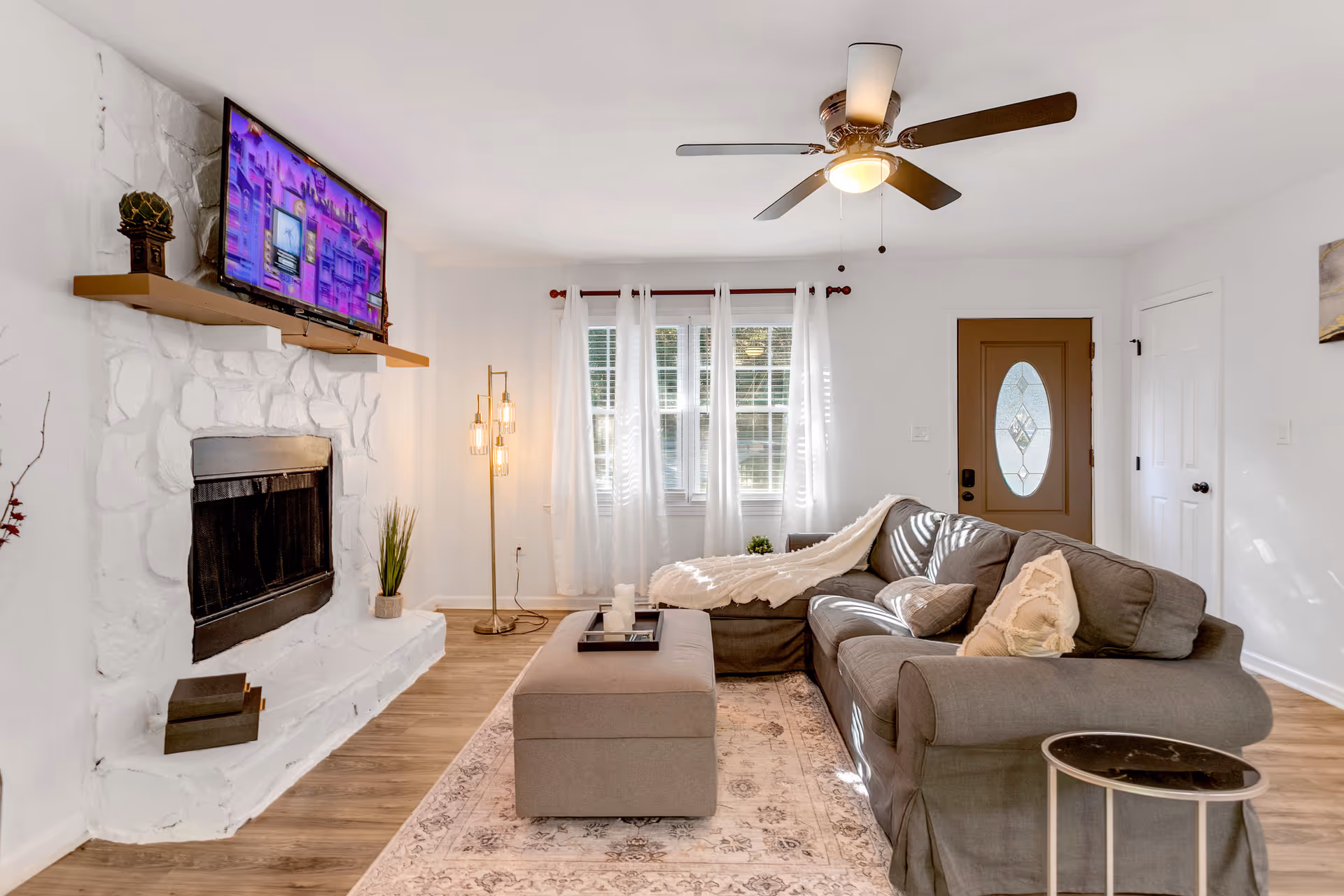 Cozy living room with white stone fireplace, TV, and gray sectional.