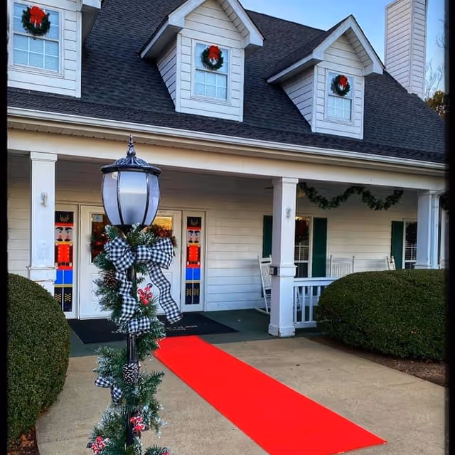 Exterior view of Greenville Glen building front with wreaths, red carpet, and lamppost.