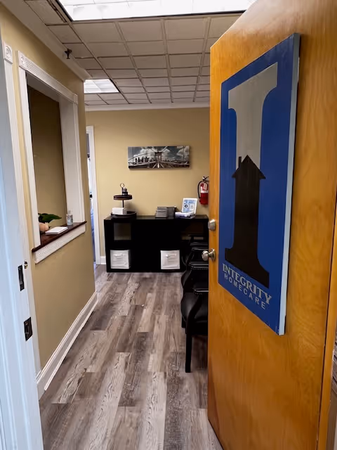 Open door reveals reception area with desk, chairs, and Integrity Home Care NY sign.