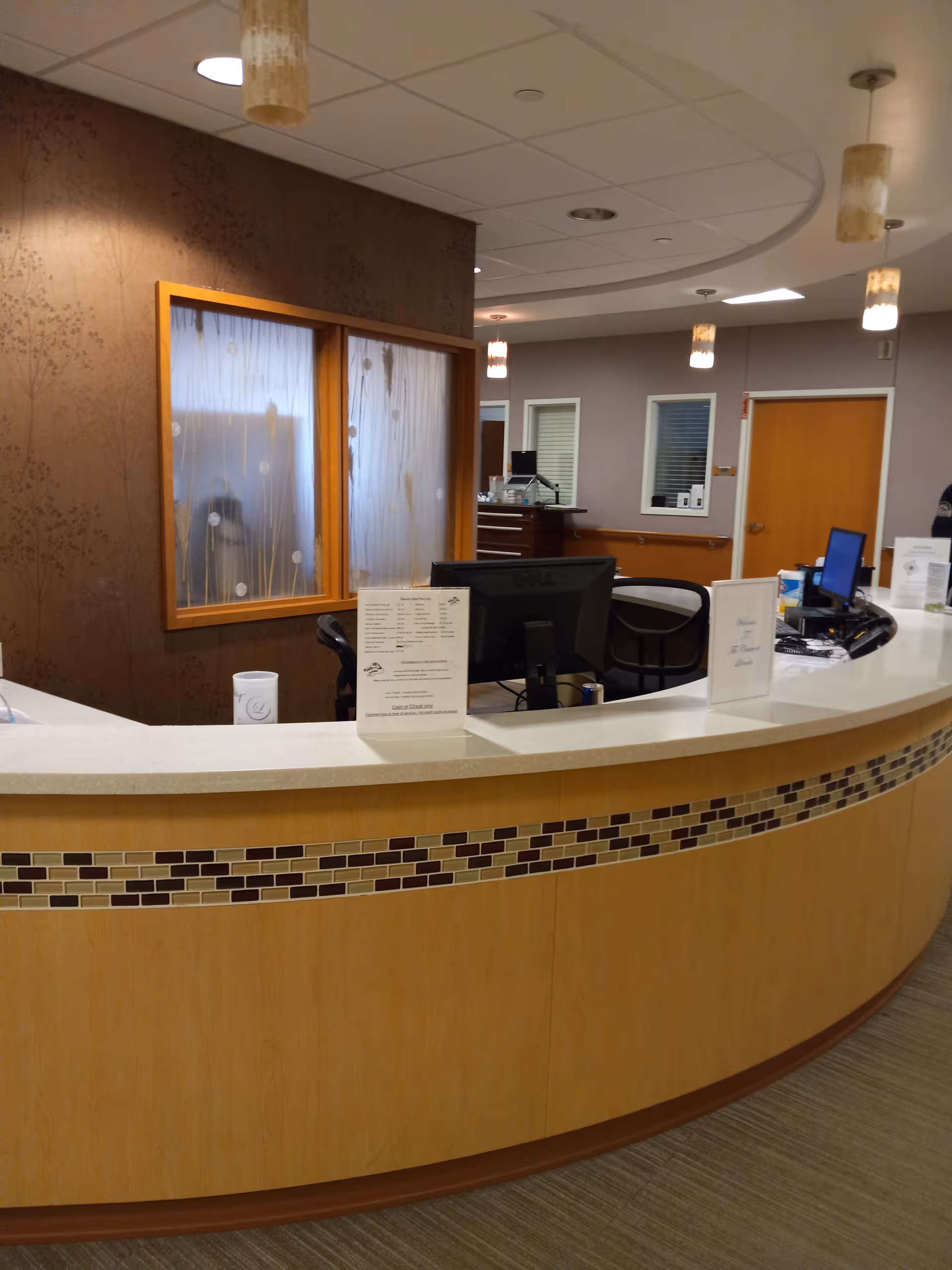 Curved reception desk in a modern senior living lobby with computers and warm lighting.