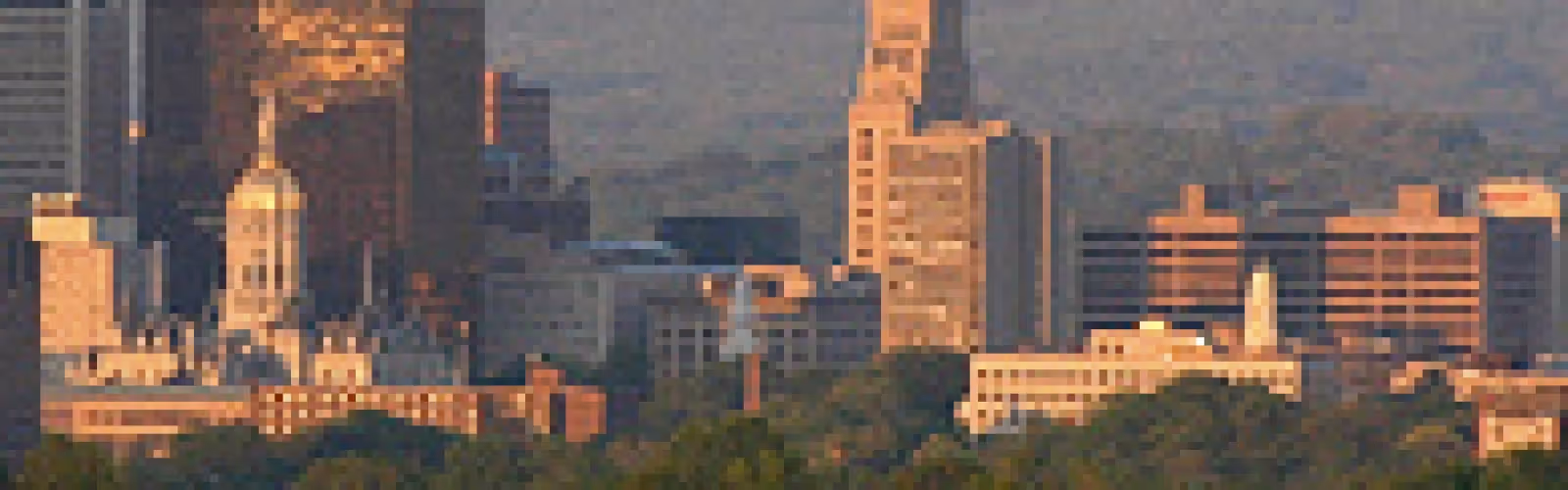 City skyline with tall buildings and warm tones in the distance.