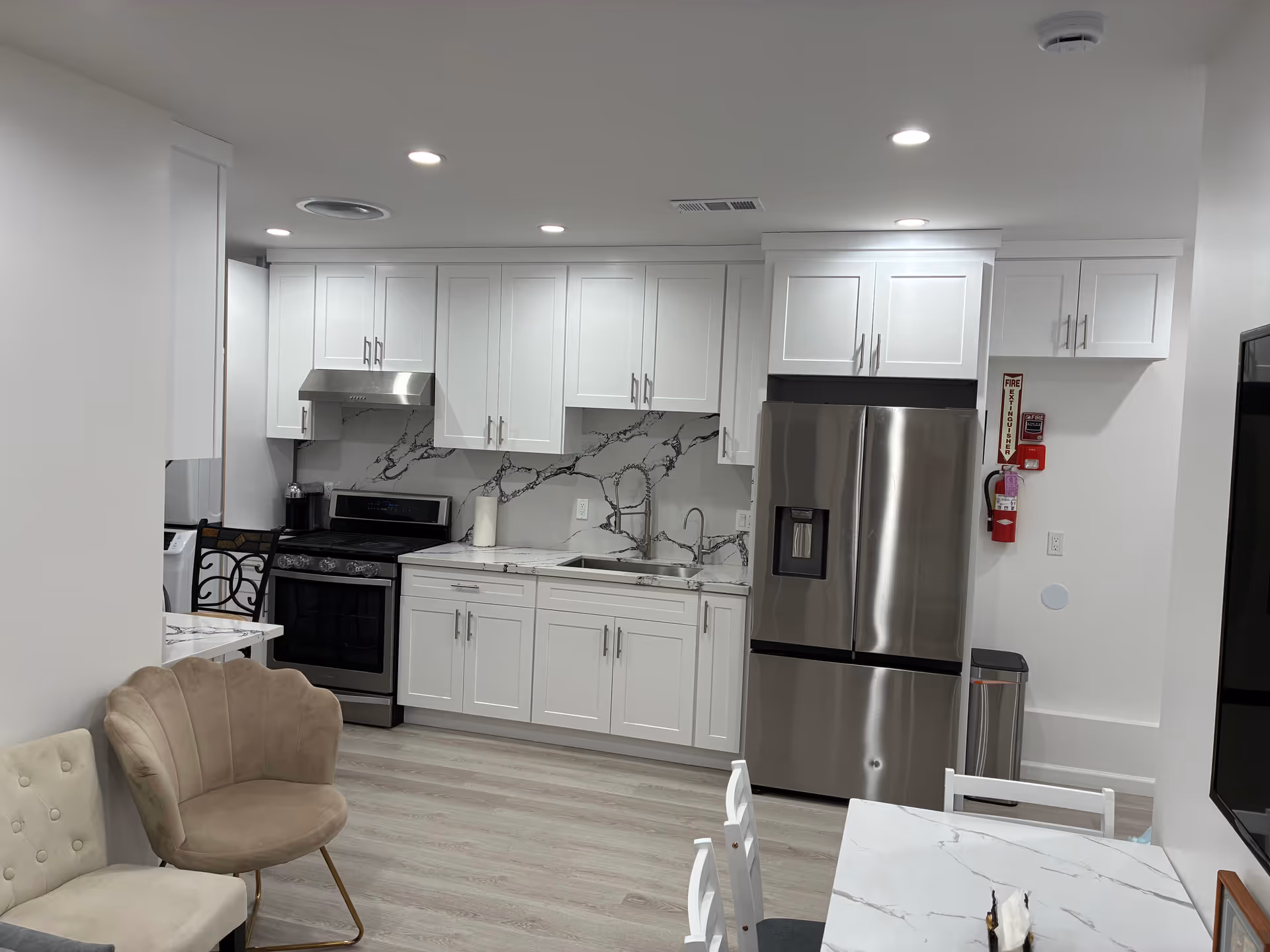 White kitchen with marble backsplash, stainless steel appliances, and dining area in a senior living facility.