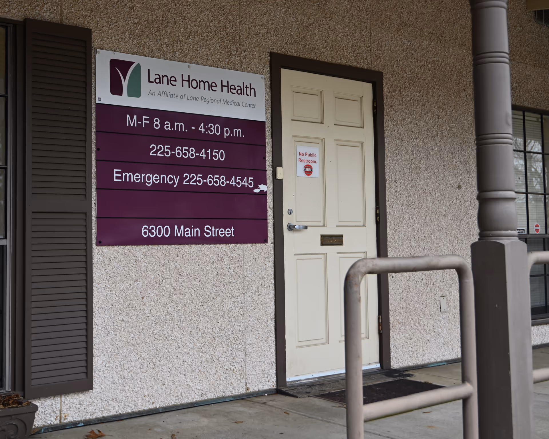 Front exterior of Lane Home Health building with sign, door, and ramp railing.