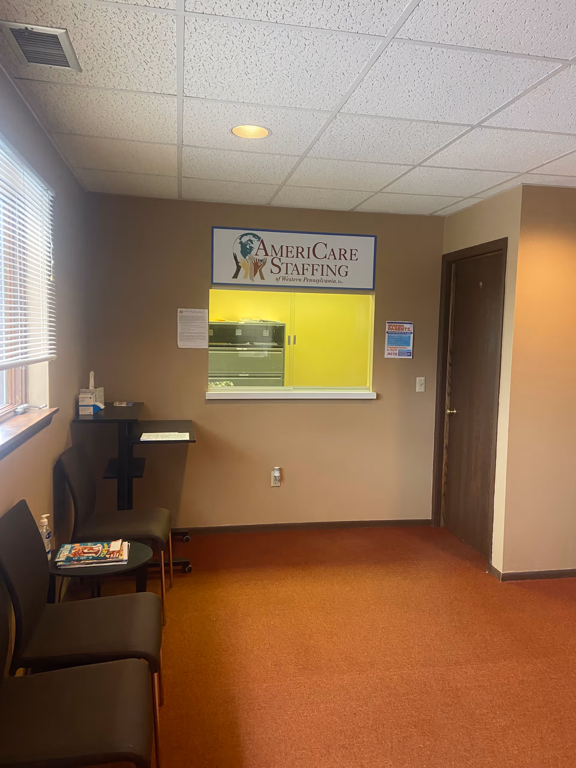 Interior waiting area with chairs, magazines, and a windowed reception labeled AmeriCare Staffing.