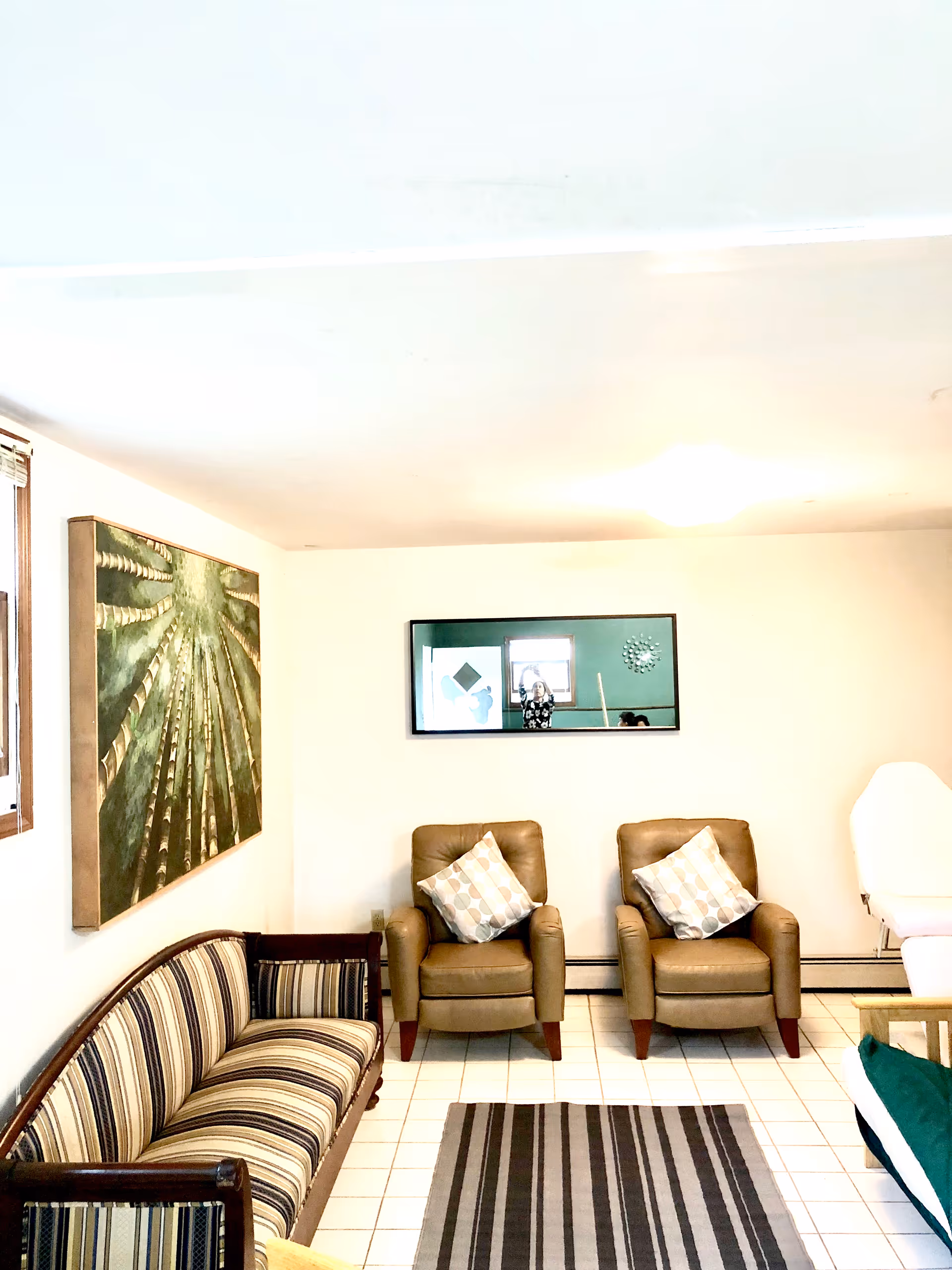 A cozy lobby area with striped sofa, two beige chairs, and wall art.