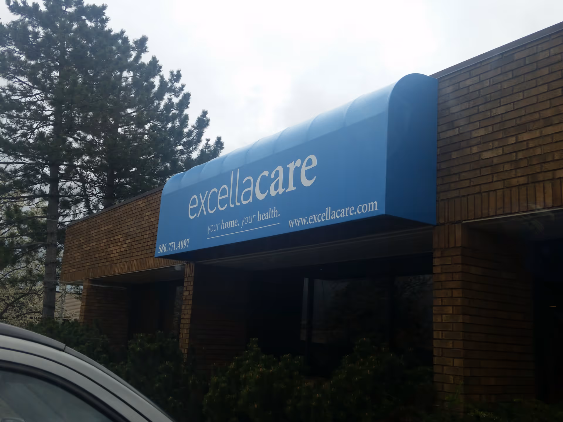 Blue awning sign reading excellacare over brick building exterior