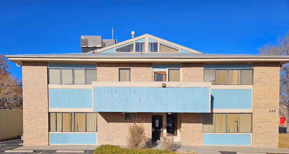 Two-story brick senior living facility with blue panels and central entrance.