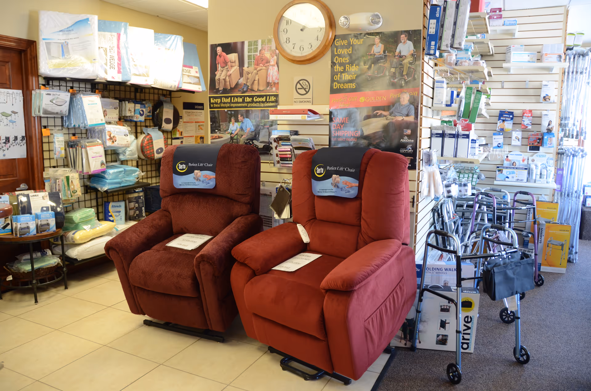 Two red recliner chairs sit in a showroom surrounded by medical supplies and posters.