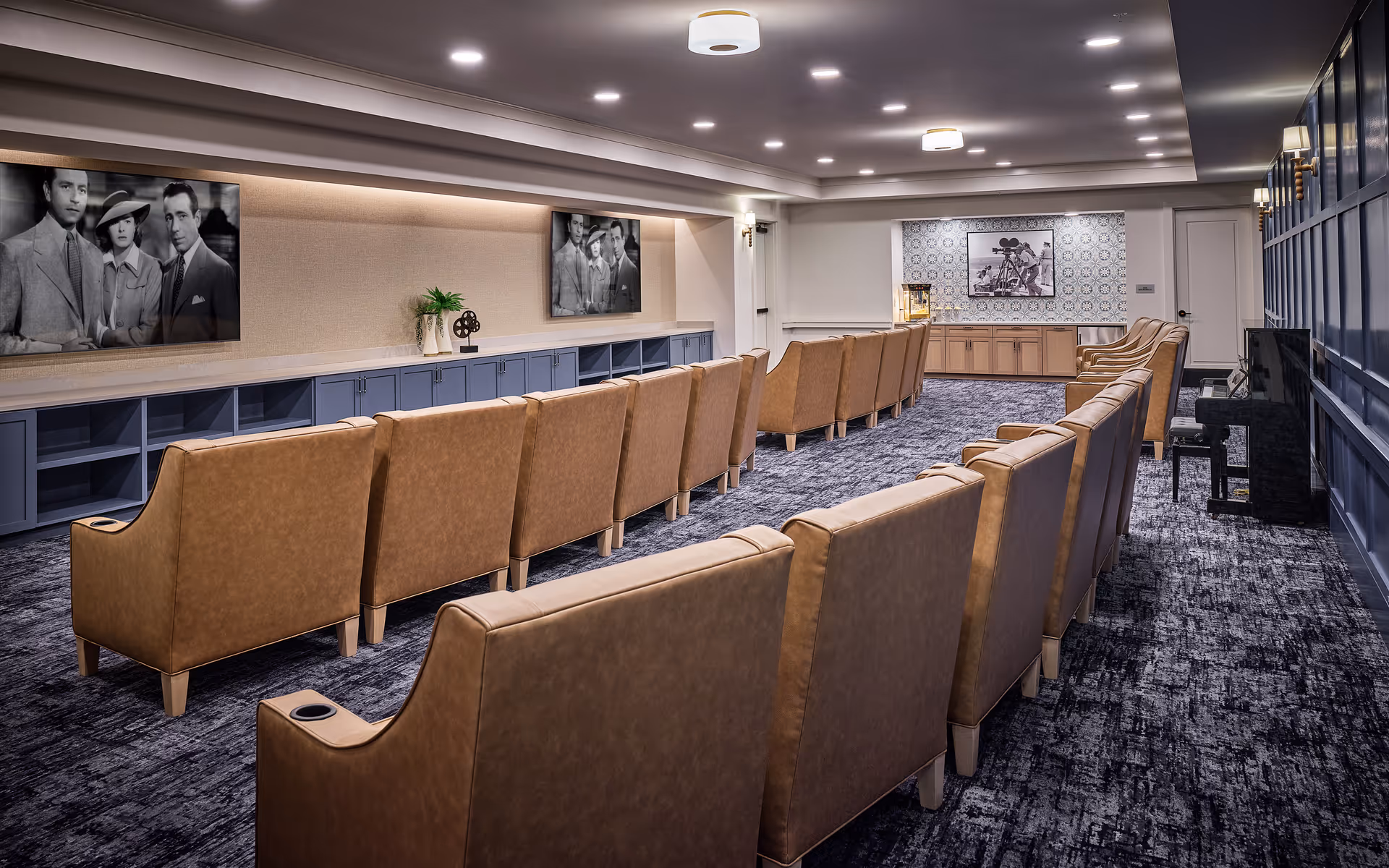 Rows of tan upholstered chairs face a wall with black-and-white photos in a modern lounge.
