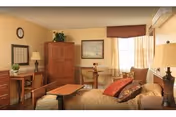 Cozy senior living room with sofa, chairs, lamps, and a wooden cabinet.
