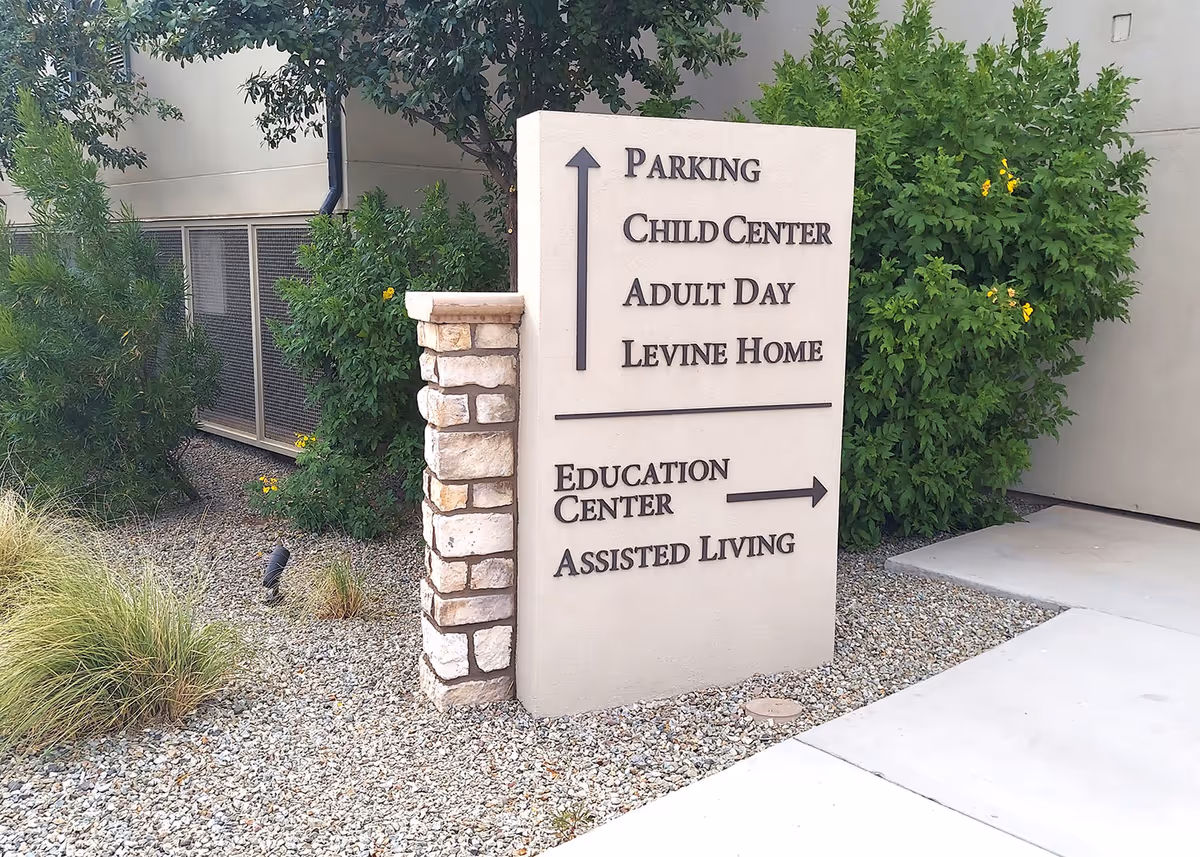 Exterior sign shows directions to Parking, Education Center, and Assisted Living