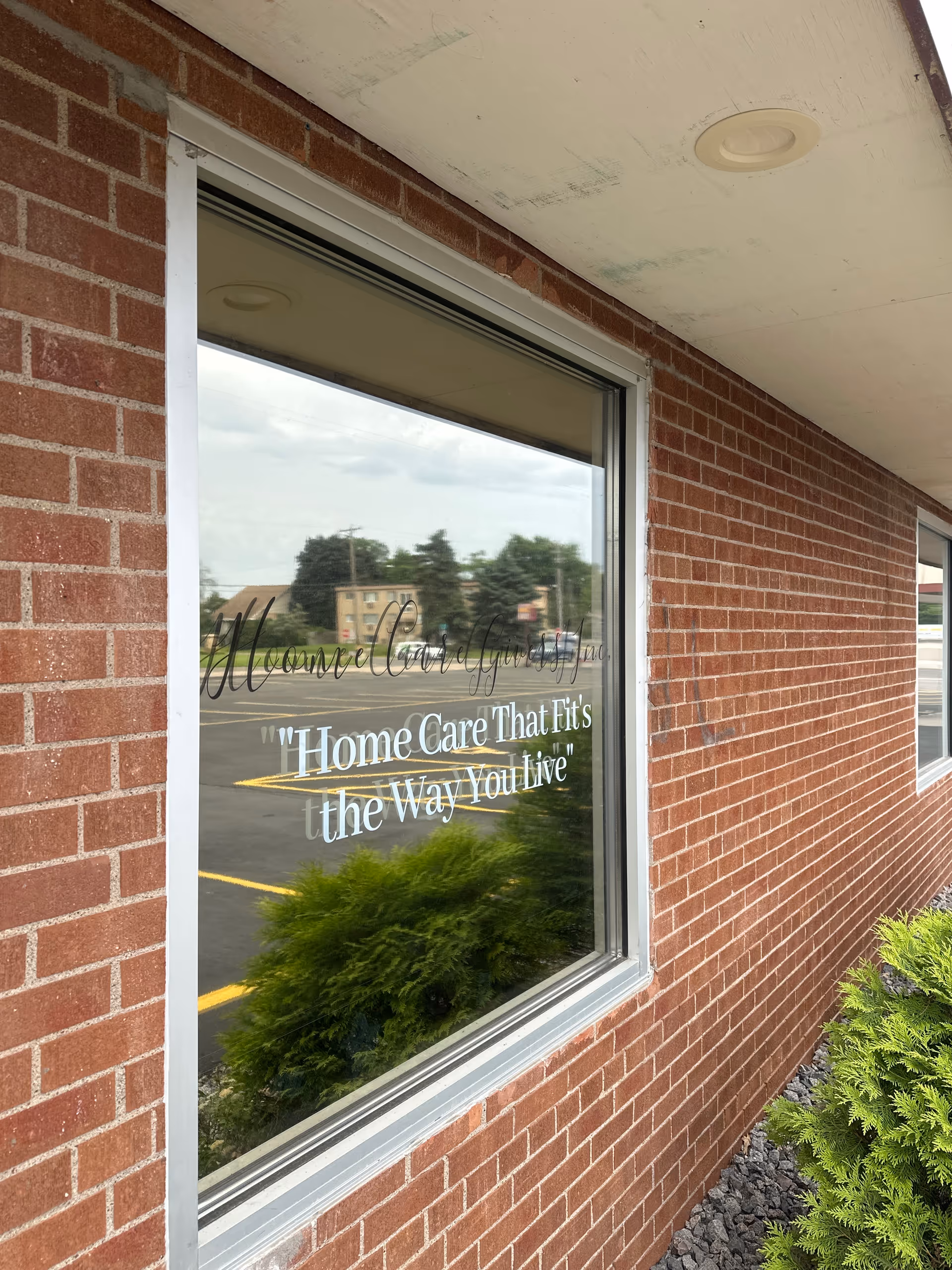 Brick facility exterior with window sign reading 'Home Care That Fits the Way You Live'.