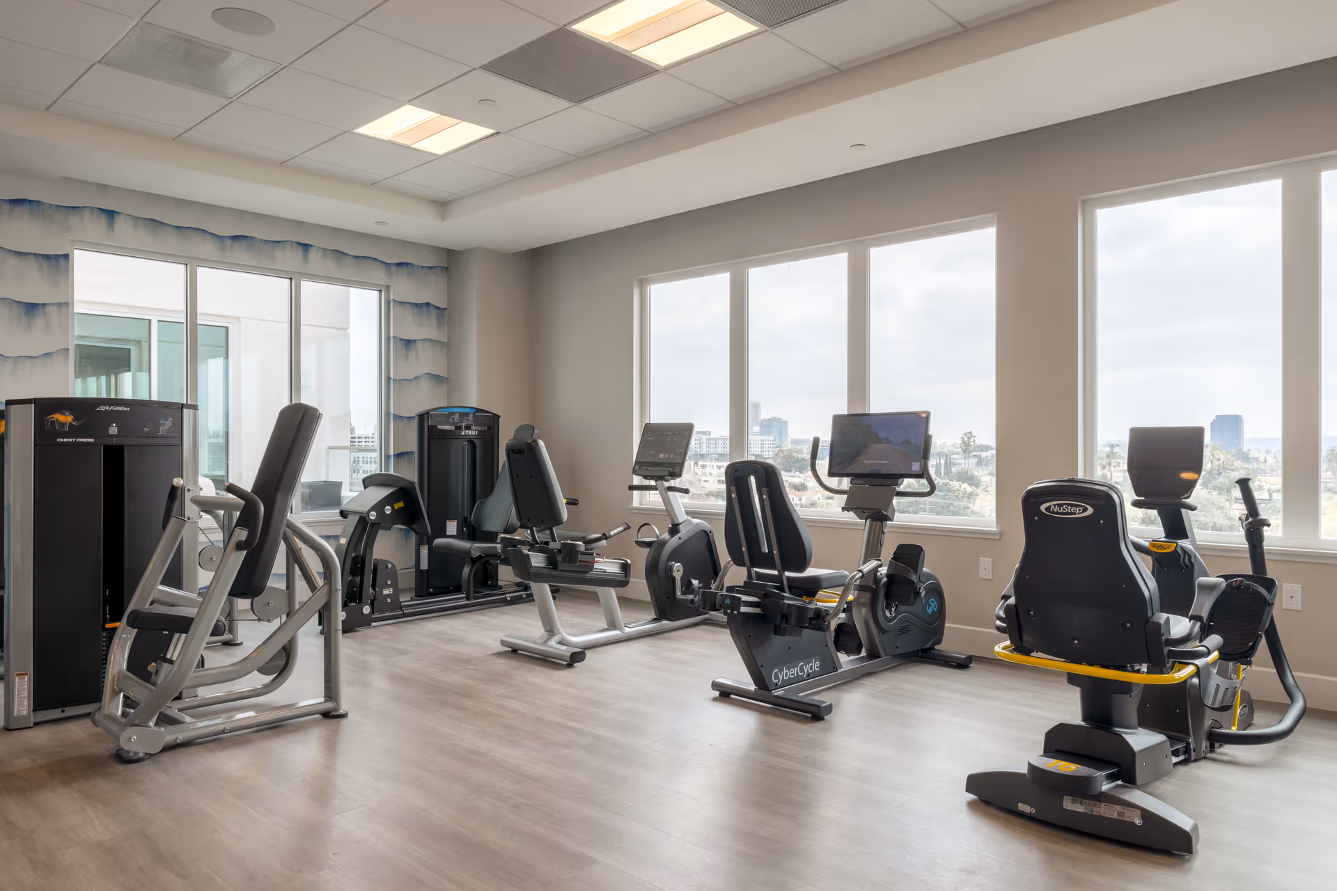 Bright interior of a senior living fitness center with cardio machines.