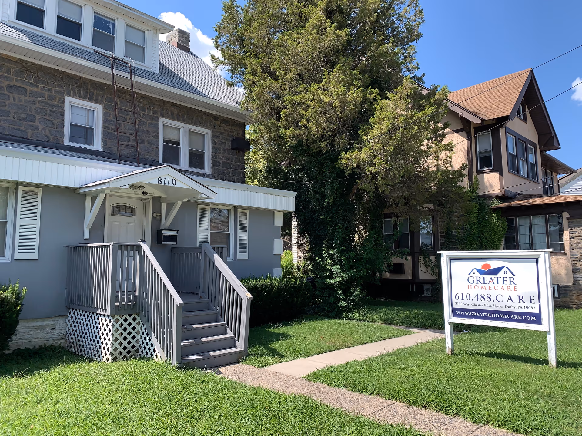 Exterior view of a Greater Homecare Services facility with stairs, a sign, and a lawn.