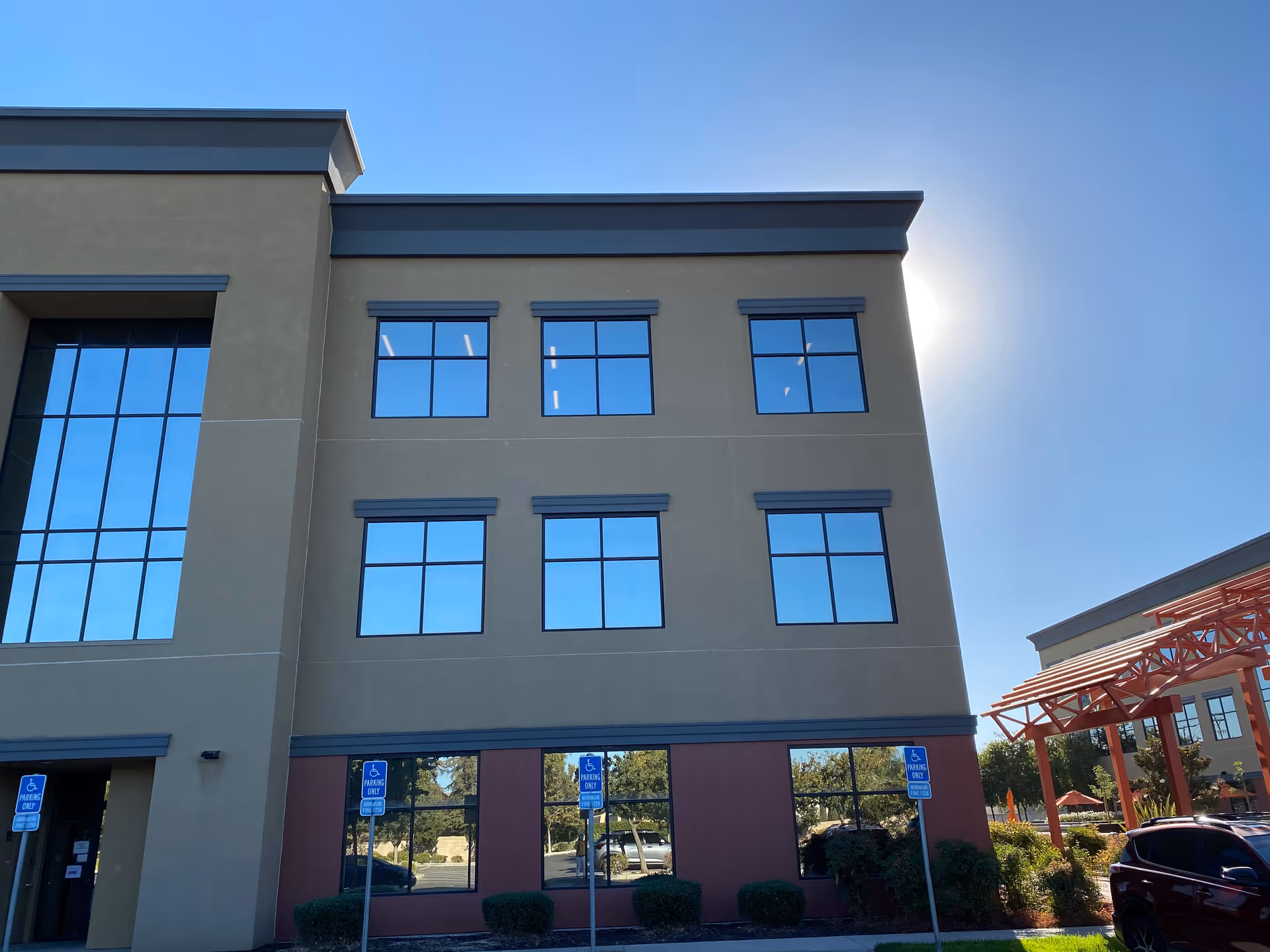 Facade of Seva Hospice building with large windows, parking, and a blue sky.