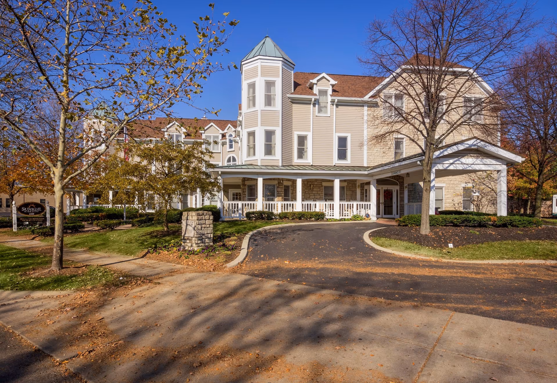 Exterior view of a multi-story senior living facility with a covered entrance and landscaped grounds.