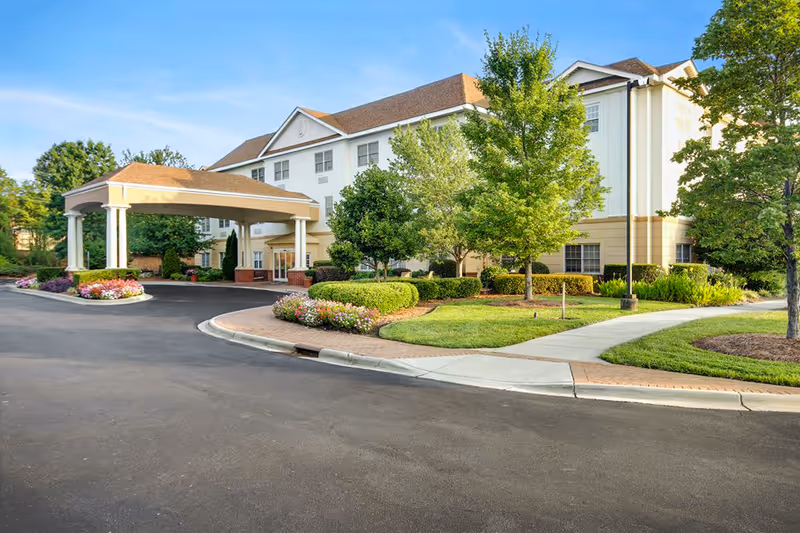 Exterior view of The Charlotte senior living facility with entrance and landscaped grounds.