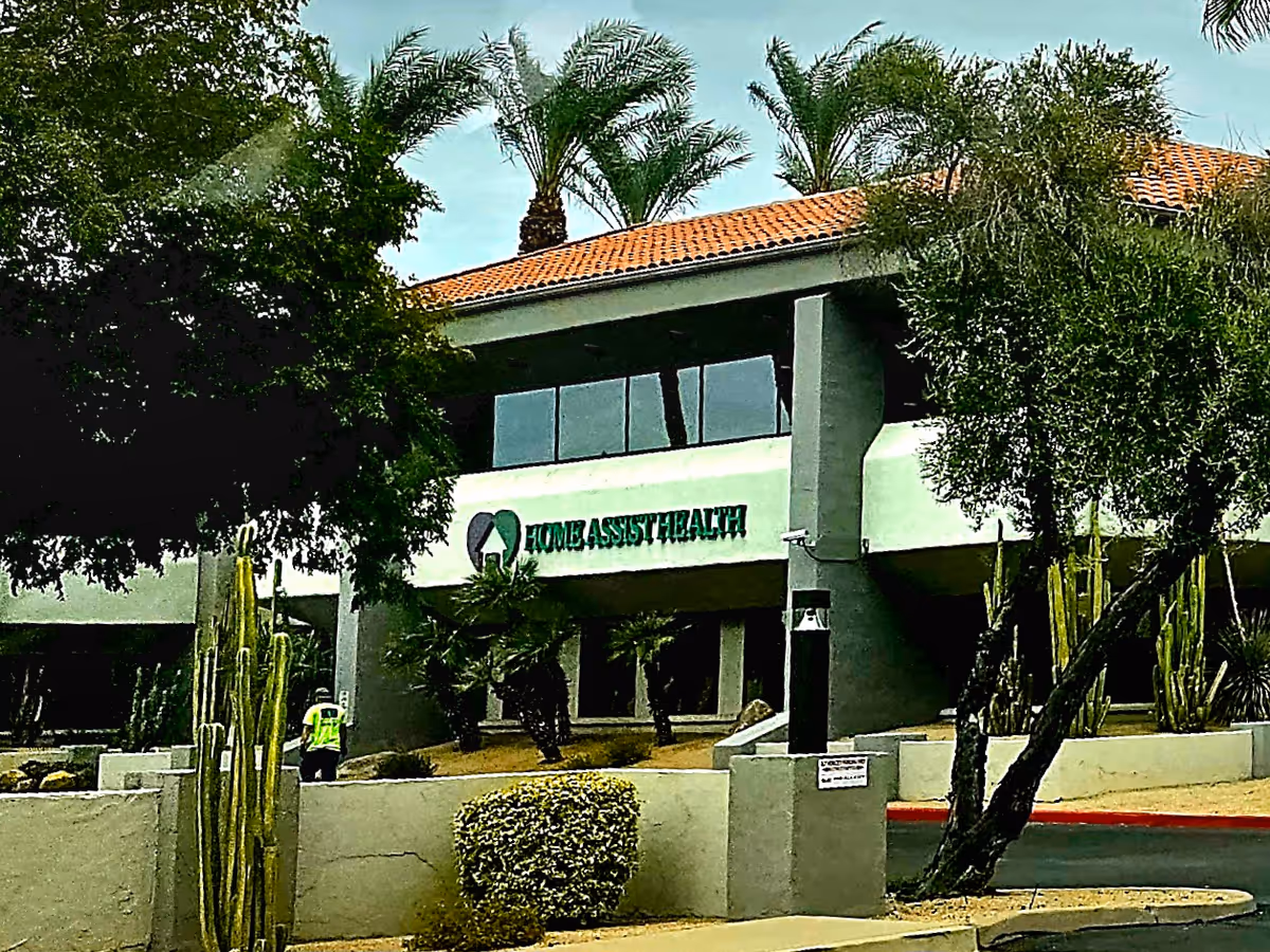 Exterior view of a care facility with Home Assist Health sign and landscaping.