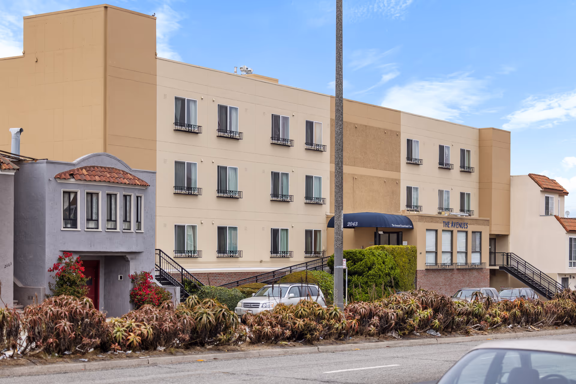 Exterior view of The Avenues Transitional Care Center, a beige multi-story building with windows.