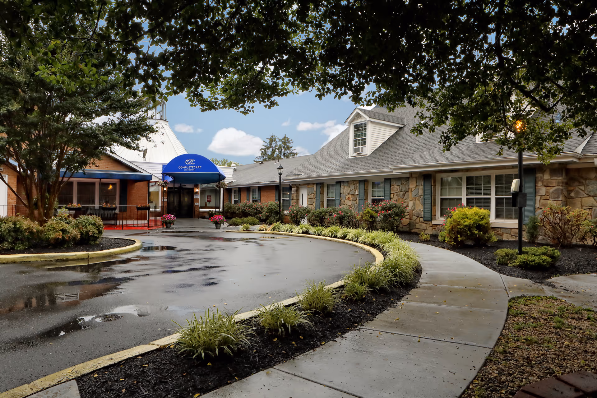 Exterior view of Genesis Springbrook senior living facility with curved walkway and landscaped entrance.