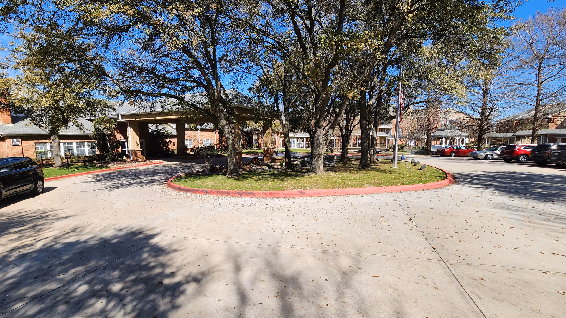 Exterior of Brookdale Club Hill with circular drive, entry, trees, and parked cars