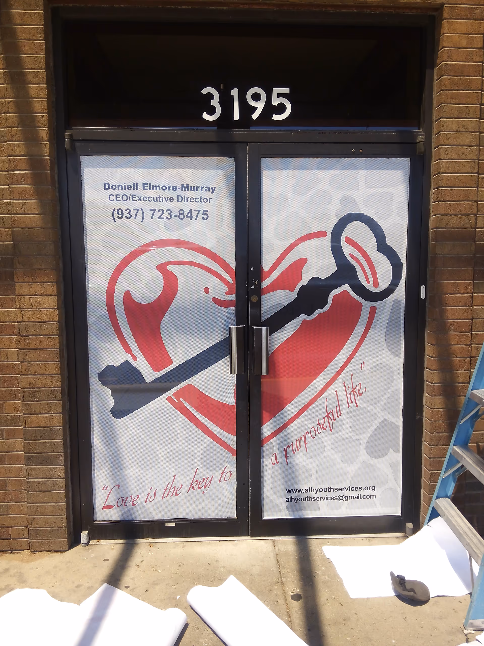 Front door with a large heart logo and brick facade, street number 3195.
