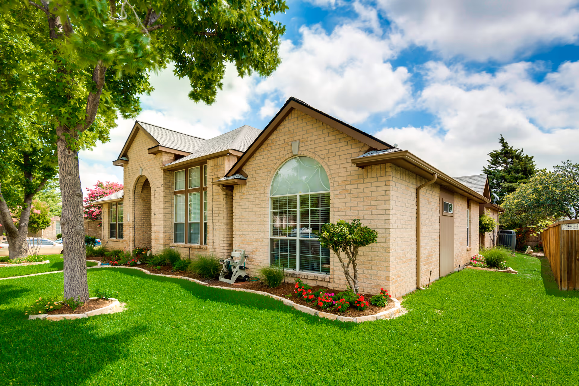 A single-story brick senior living home with a manicured lawn and trees.