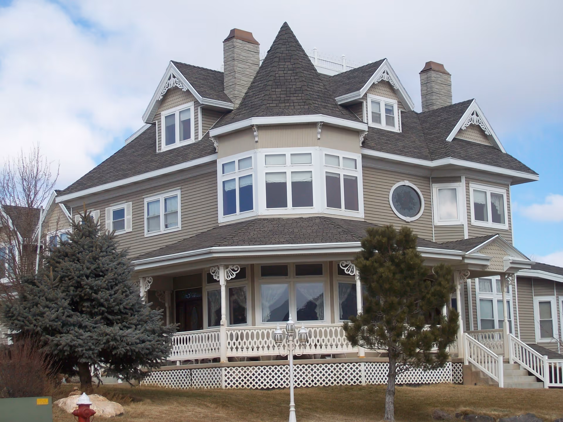 A large Victorian-style senior living facility with a wraparound porch and peaked roof.