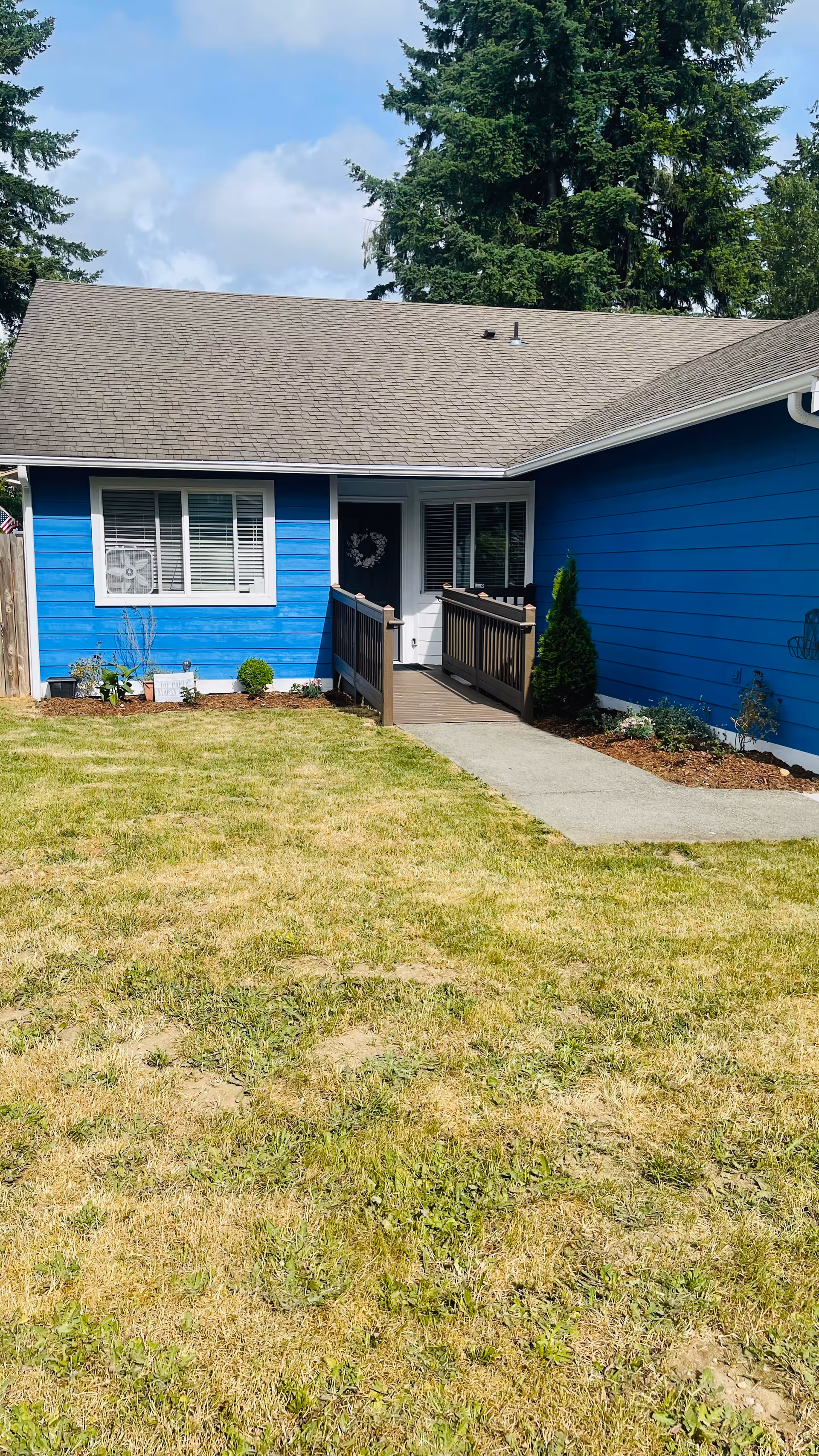 Blue, single-story facility exterior with a ramp entry and small front lawn.