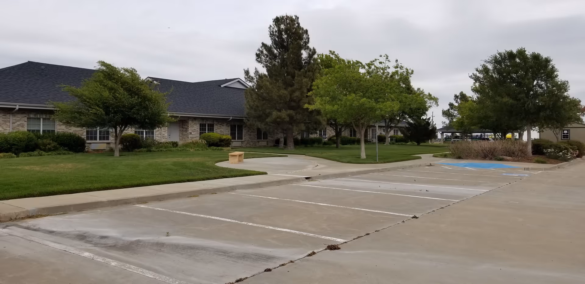 Exterior view of The Seasons Assisted Living with parking lot and trees.